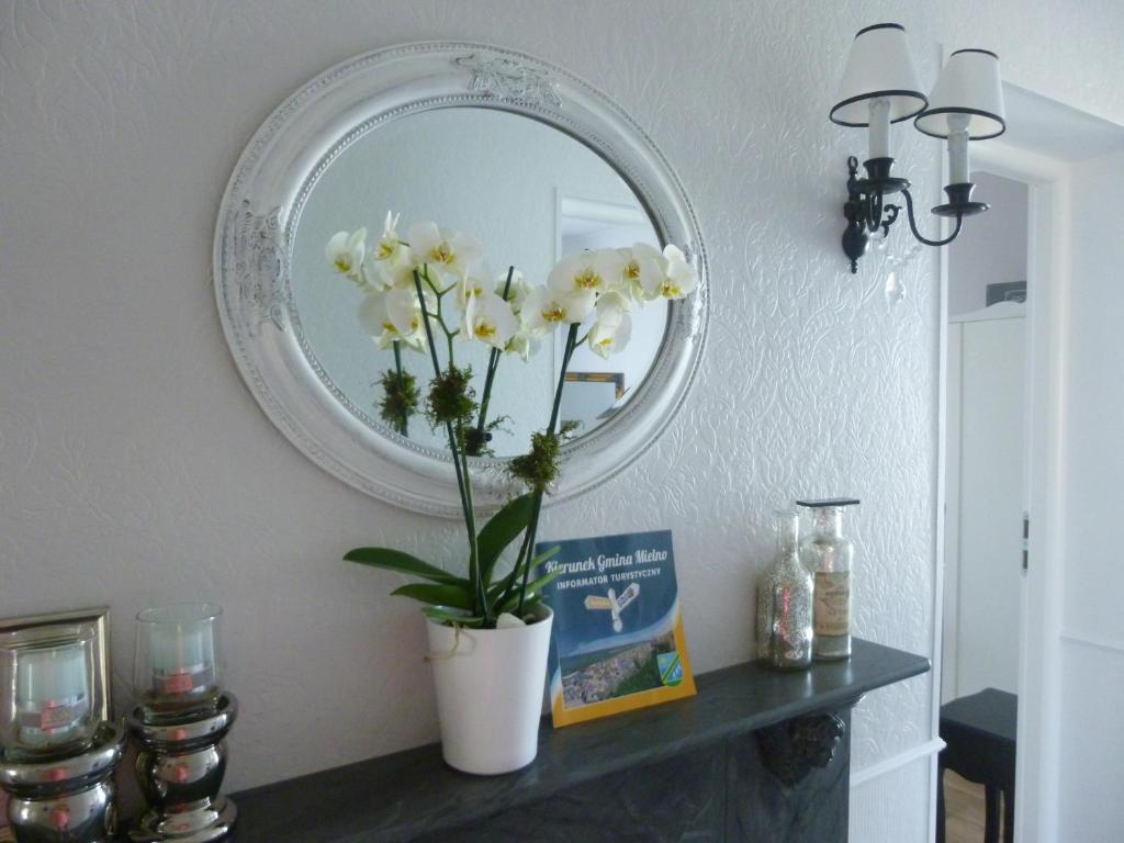 a vase of flowers on a table in front of a mirror at Pod Aniołem in Mielno