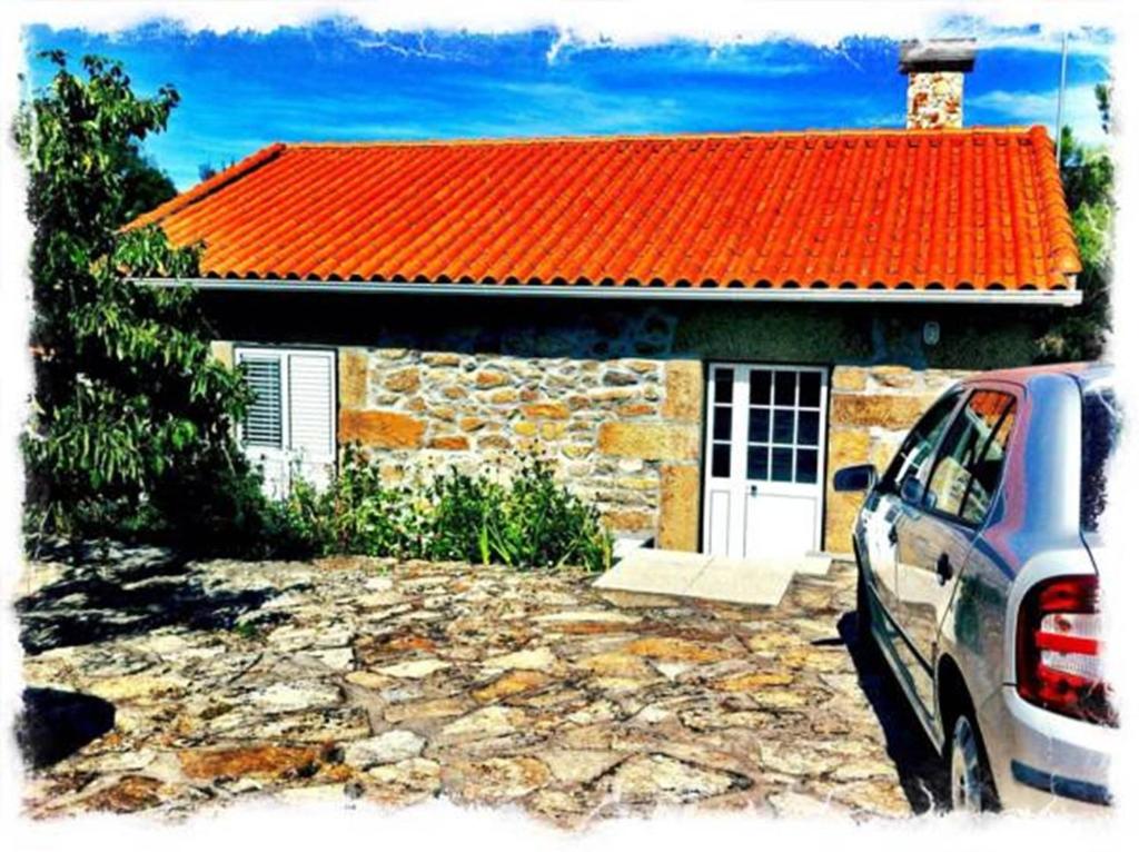 a car parked in front of a house with an orange roof at Casa de Malhoes in Vilares
