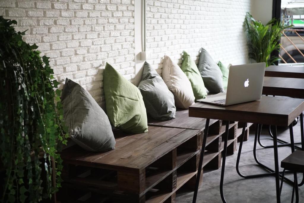 a bunch of pillows sitting on a bench with a laptop at Krit Hostel in Bangkok