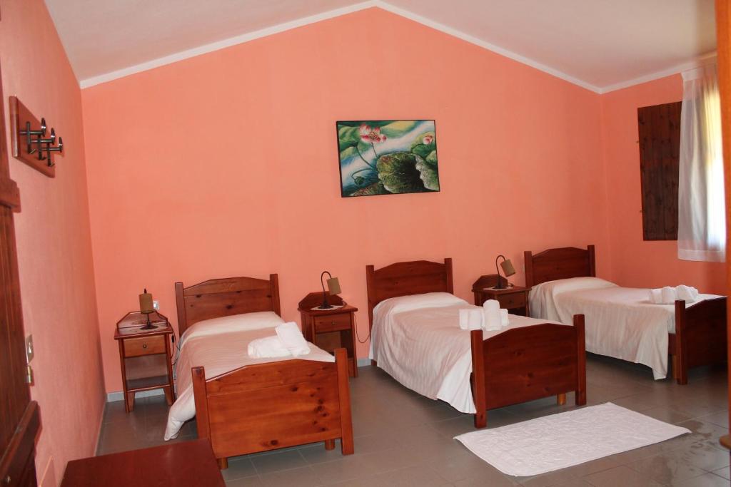 a room with three beds with orange walls at Ostello Su Mannau in Fluminimaggiore