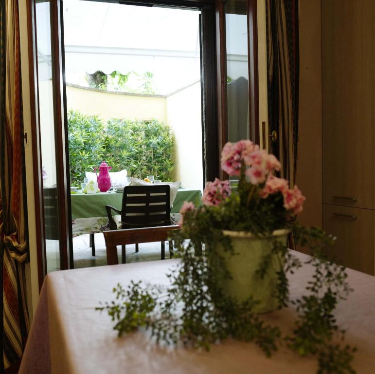 una mesa con un jarrón de flores rosas. en Sweet Central appartment, en San Benedetto del Tronto