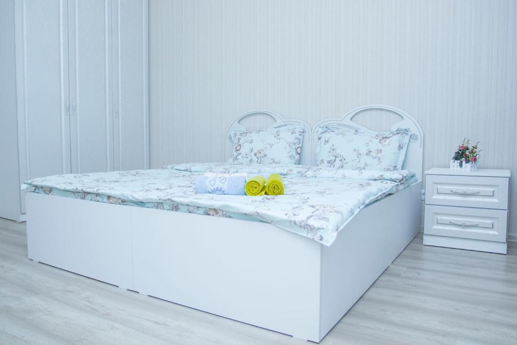 - un lit blanc avec deux chaussures jaunes dans l'établissement Luxury apartment Promenade Expo, à Astana