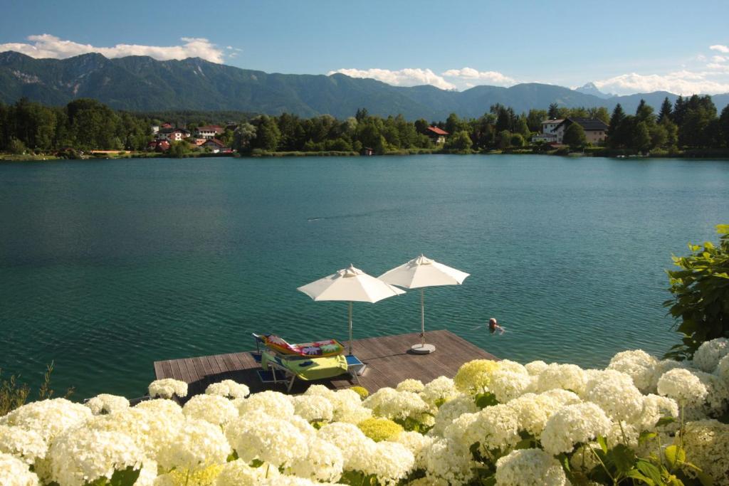 a lake with a table and umbrellas in the water at Villa Mayr in Villach