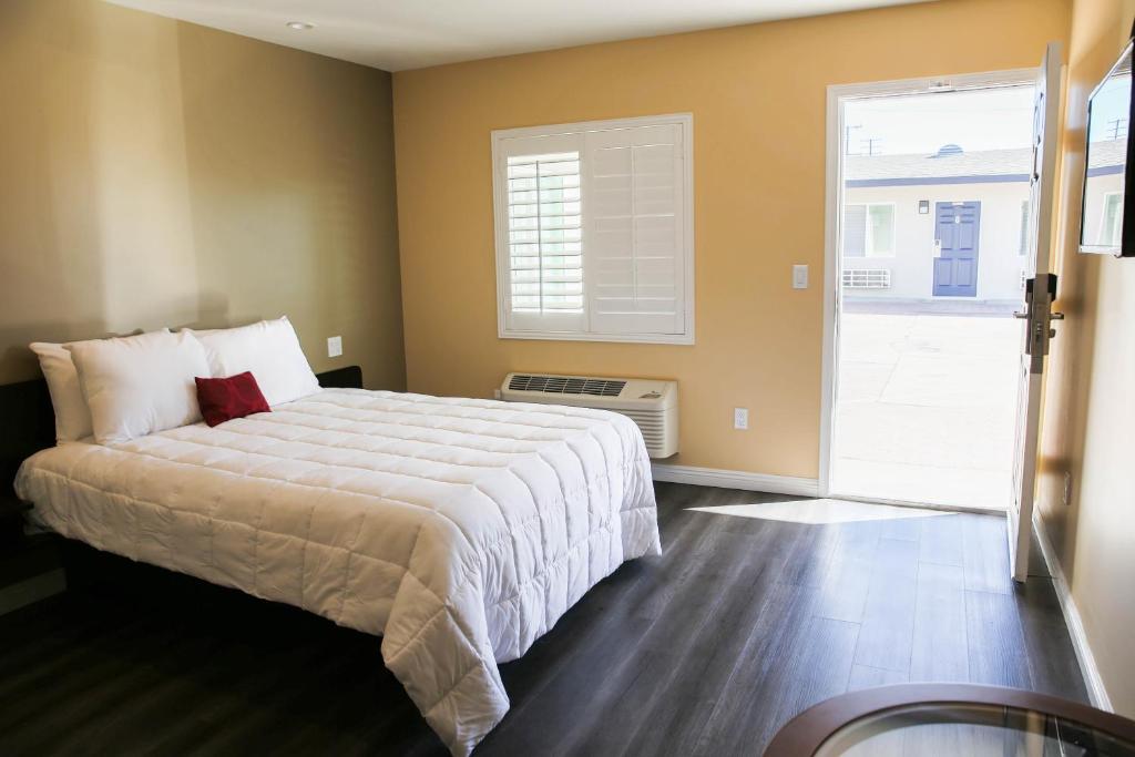a bedroom with a bed and a large window at Newport Bay Inn in Costa Mesa