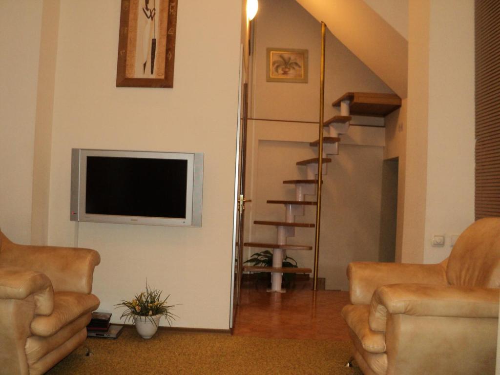 a living room with two chairs and a flat screen tv at Guest House Valentino in Krasnodar