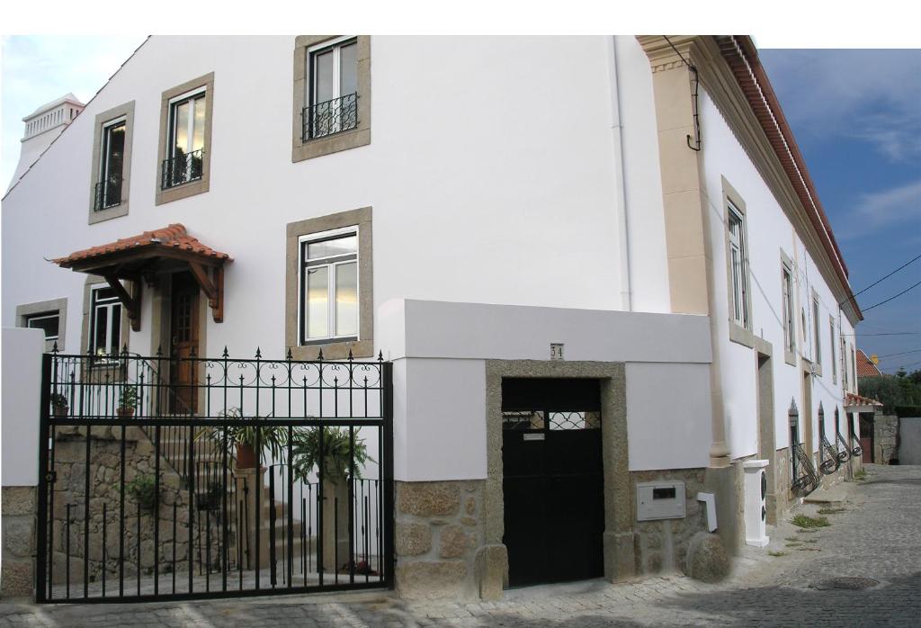 a white house with a black door and a gate at Casa do Balcão in Alcains