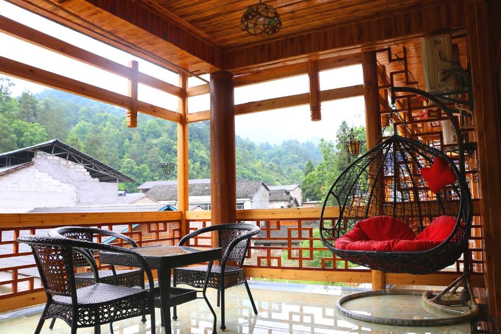 - une terrasse couverte avec des chaises, une table et une balançoire dans l'établissement Zhangjiajie one step to heaven inn (Yangjiajie ticket office), à Zhangjiajie