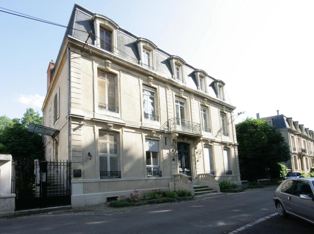 Biały dom z samochodem zaparkowanym przed nim w obiekcie L'Hôtel Particulier - Appartements d'Hôtes w Nancy