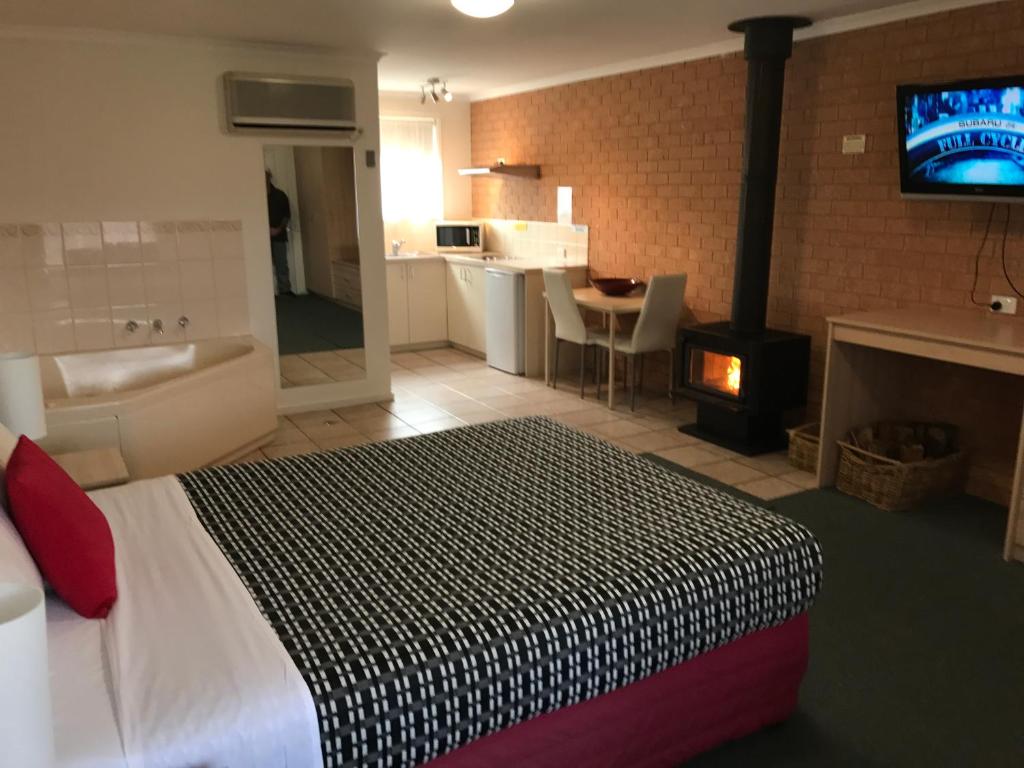 1 dormitorio con 1 cama, chimenea y TV en Beachcomber Motel & Apartments en Apollo Bay