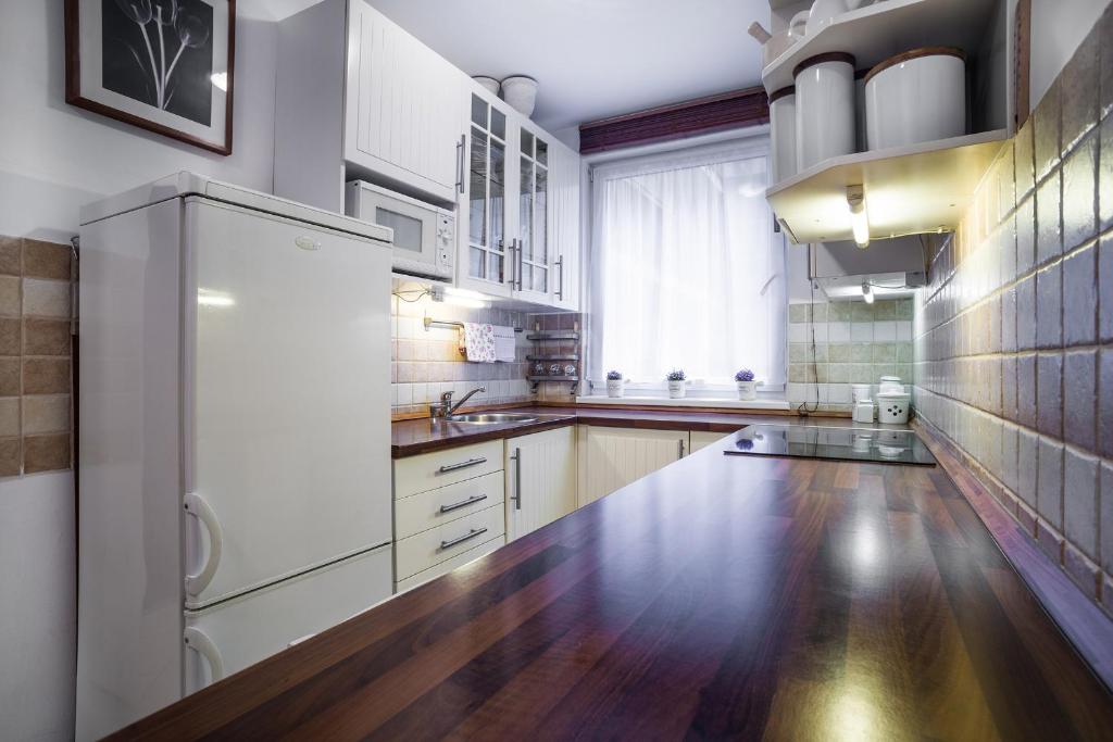 a large kitchen with white appliances and wooden floors at Lovely Corvin Apartment in Budapest
