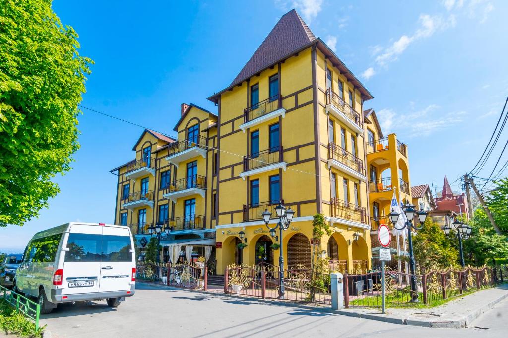 una furgoneta blanca estacionada frente a un edificio amarillo en Princess Elisa Hotel en Zelenogradsk