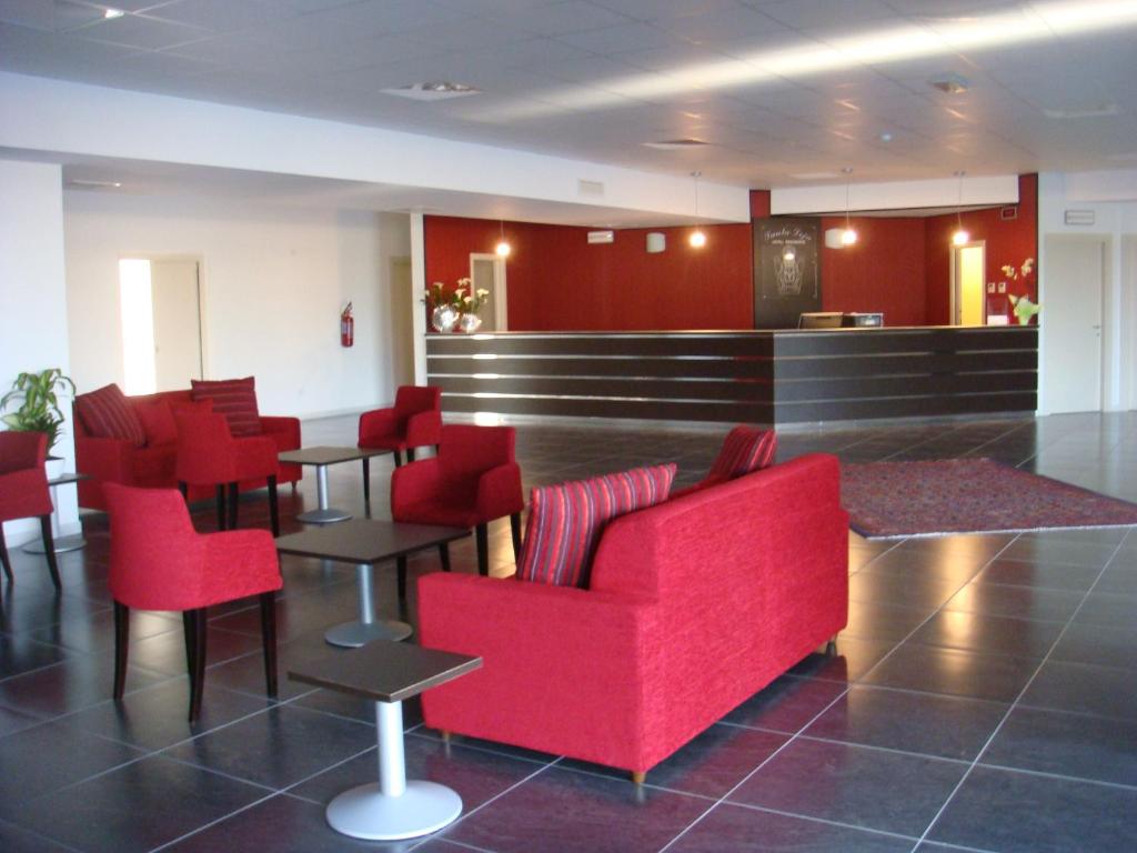 a waiting room with red chairs and a bar at Santa Loja Hotel Residence in Tito