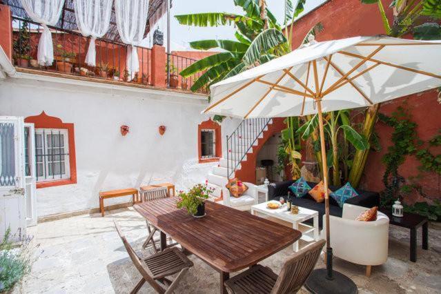 a patio with a wooden table and an umbrella at Apartamentos El Patio Andaluz in Jerez de la Frontera
