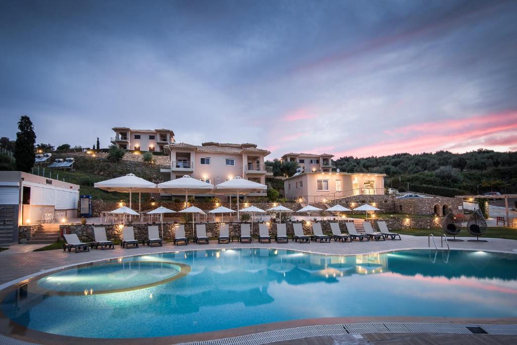 una piscina con sedie e ombrelloni in un resort di Baywatch Hotel a Chrani