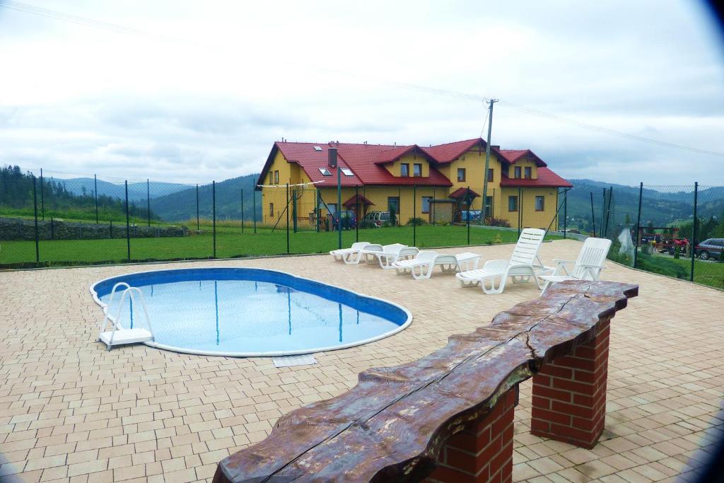 a swimming pool with chairs and a house in the background at u Wilczka in Zwardoń