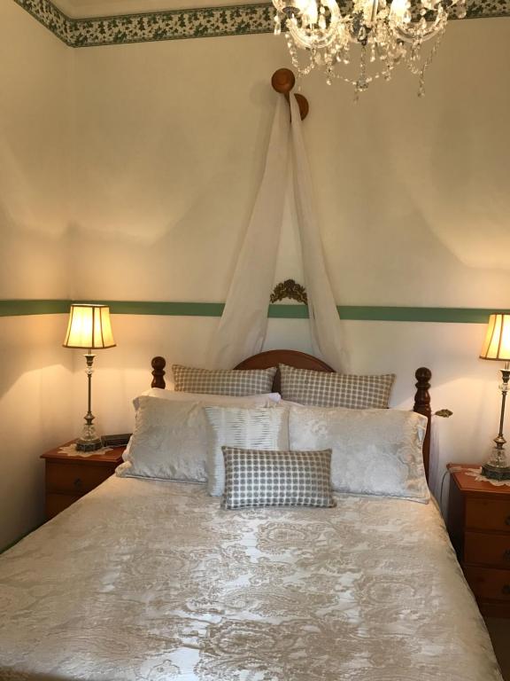 a bedroom with a bed with two lamps and a chandelier at Guest House on Hyde in Bellingen
