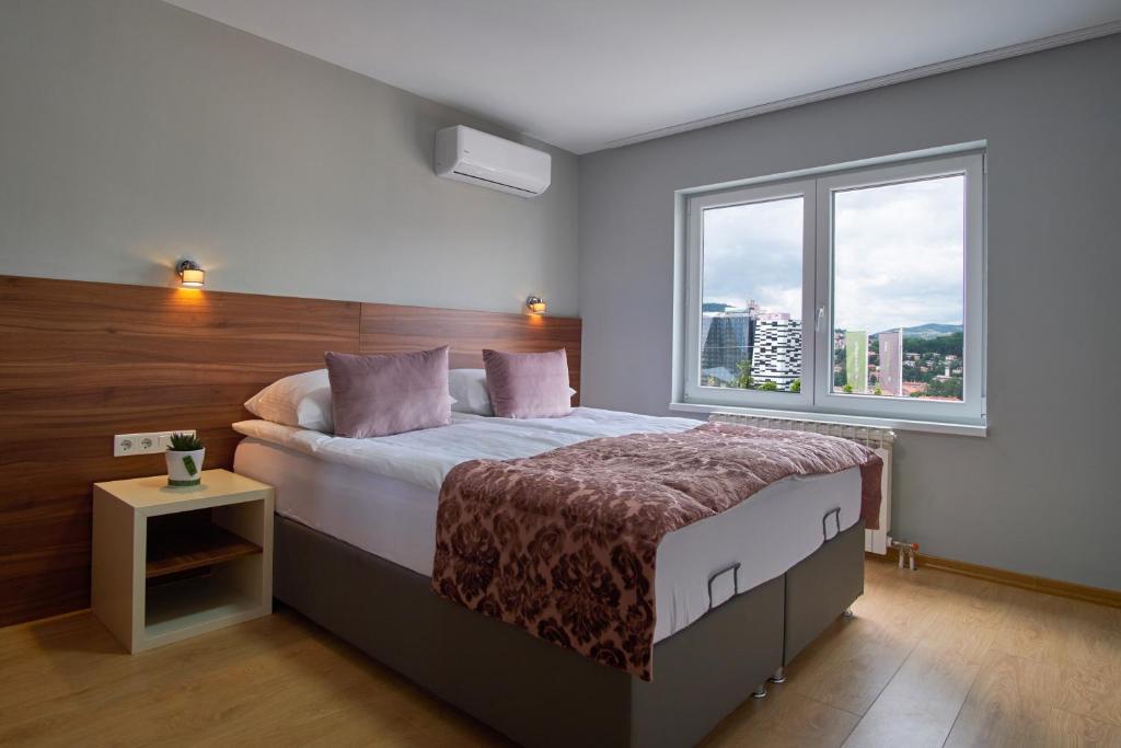 ein Schlafzimmer mit einem Bett und einem großen Fenster in der Unterkunft Green Elite Residence in Sarajevo
