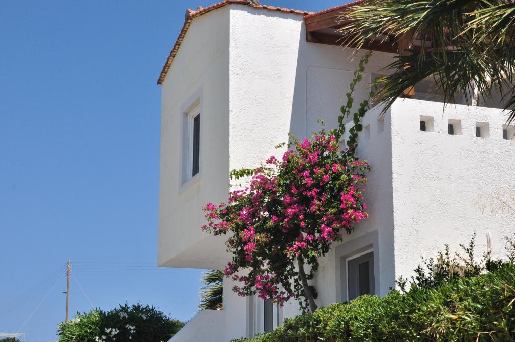 a white building with pink flowers on the side of it at Castri Village Hotel in Palekastron