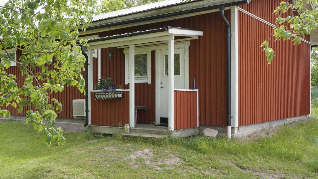 una casa roja con una puerta blanca y un porche en Mårbys Gästrum, en Mårby