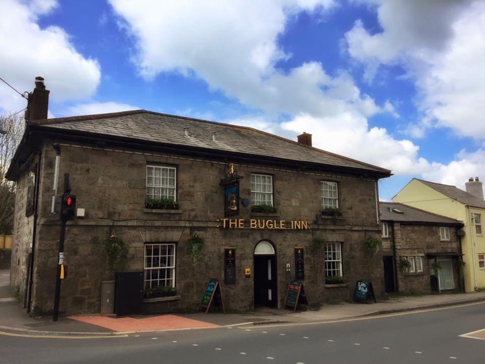 an old brick building on the corner of a street at The Bugle Inn in St Austell