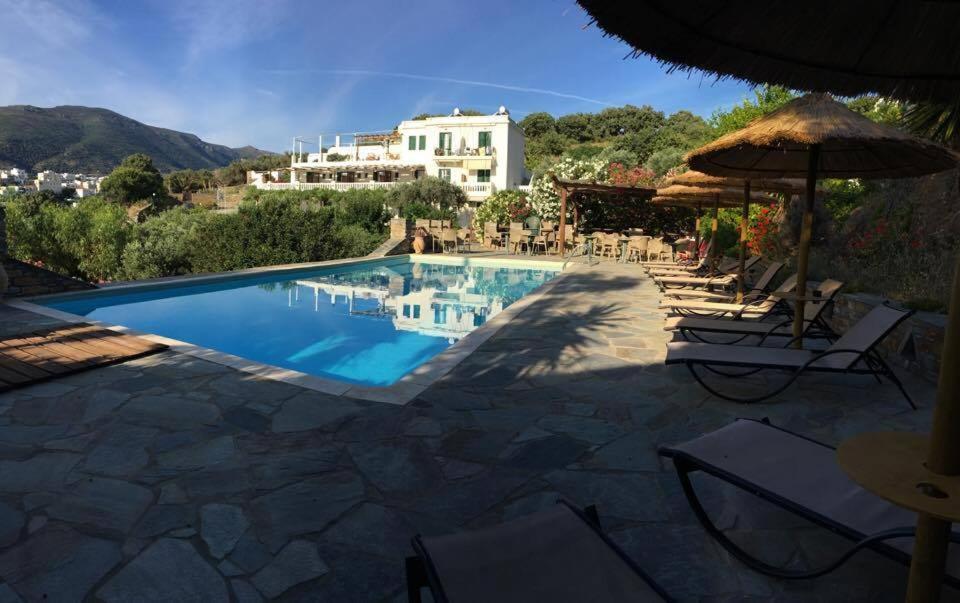 een zwembad met stoelen en een huis op de achtergrond bij Vassiliki Studios in Ándros