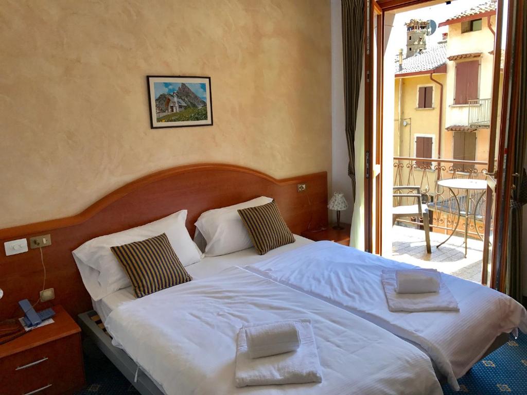 a bedroom with a large bed with a balcony at Garnì Hotel Tignale, GTSGroup in Tignale