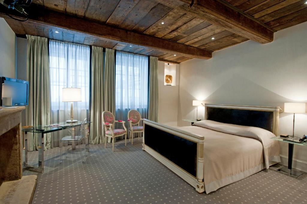 a bedroom with a bed and a table and chairs at Hotel Le Place d'Armes - Relais & Châteaux in Luxembourg