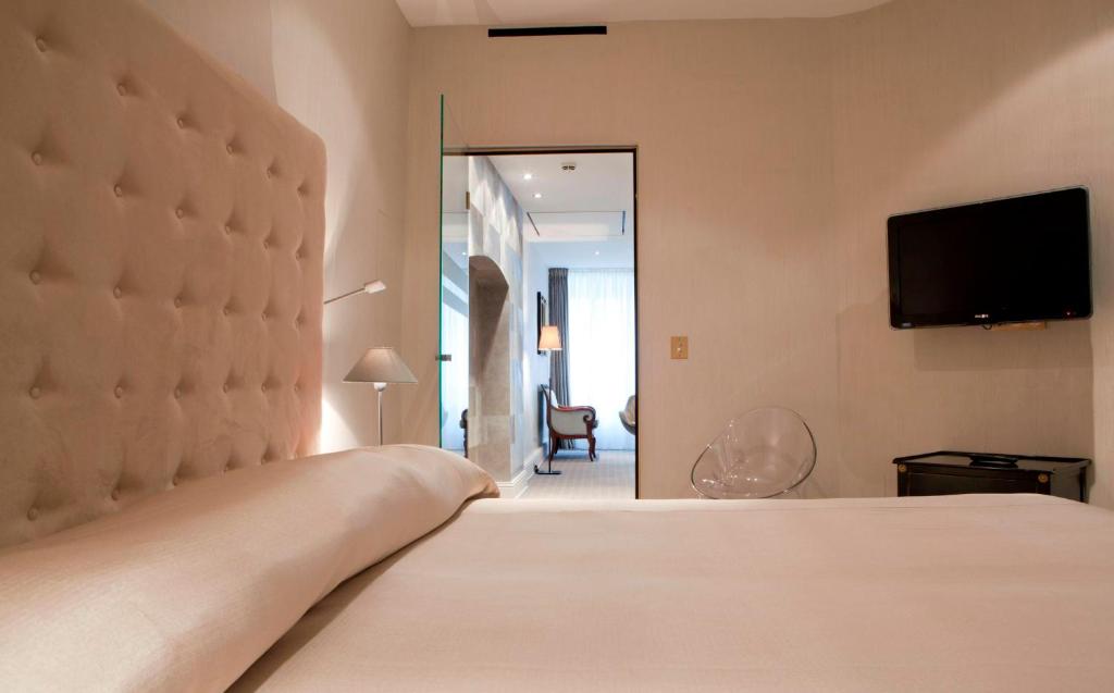 a bedroom with a bed and a tv on the wall at Hotel Le Place d'Armes - Relais & Châteaux in Luxembourg