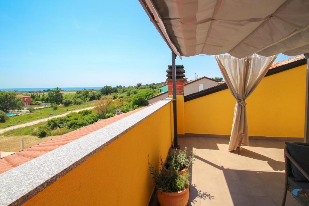 a balcony with a yellow wall and a umbrella at Apartments Jadranka Sain in Novigrad Istria