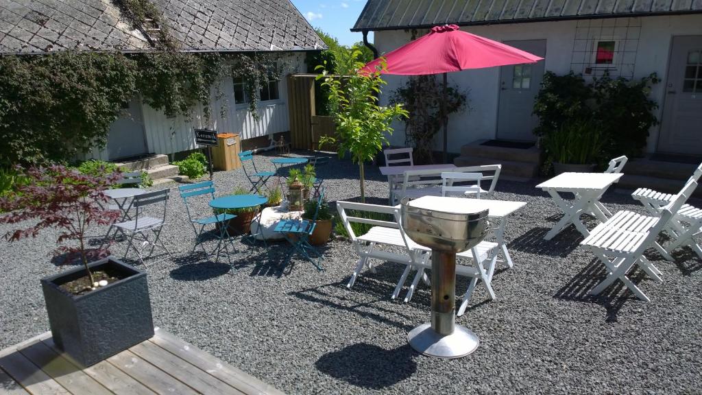 a patio with a grill and chairs and a table with an umbrella at Elisetorp in Kivik