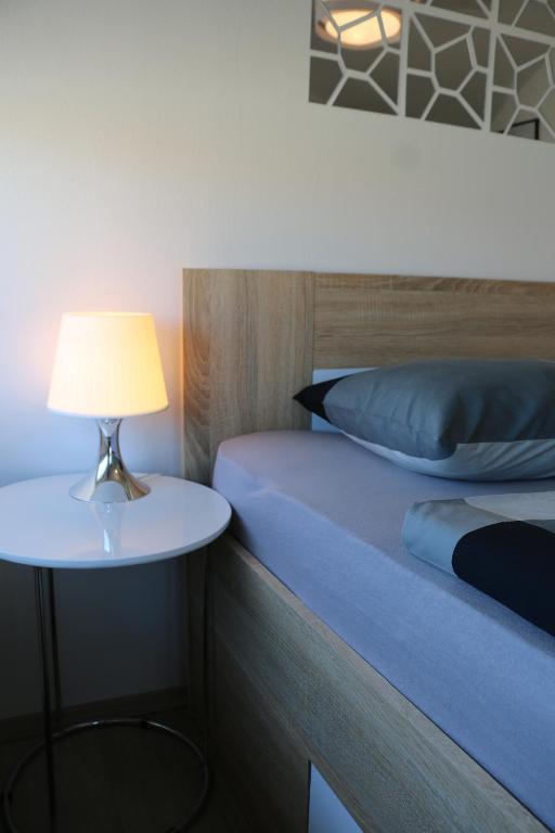 a bed and a table with a lamp on it at Luma 2 in Osijek