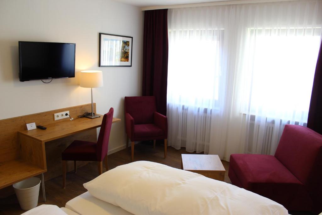 ein Hotelzimmer mit einem Bett, einem Schreibtisch und einem TV in der Unterkunft Gasthof und Pension zum Löwen in Hirschberg an der Bergstraße