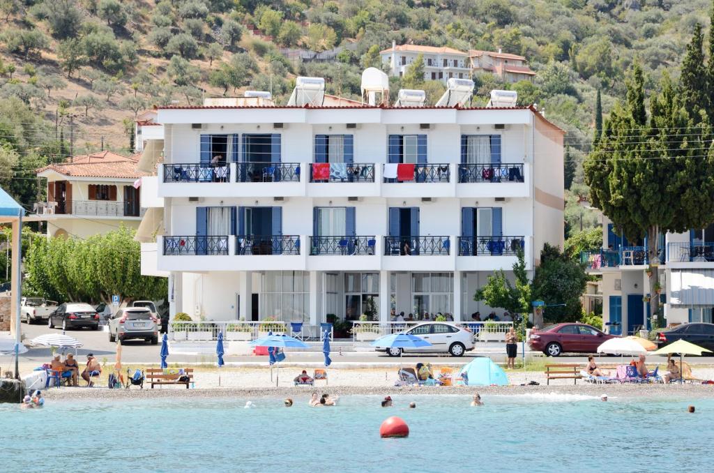 um edifício numa praia com pessoas na água em Hotel Blue Sea em Tyros