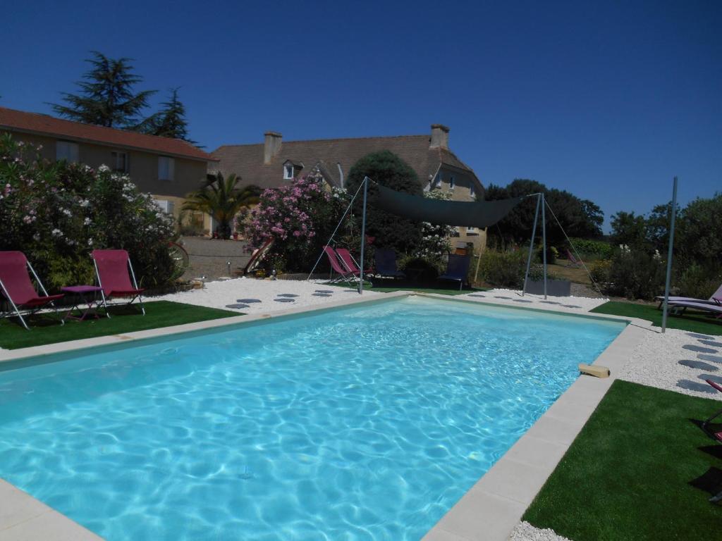 a large blue swimming pool with two chairs in a yard at Le Pressoir B&B in Aydie