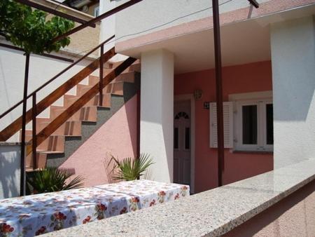 un edificio con un tavolo e scale di fronte di Apartmani Seršić a Baška