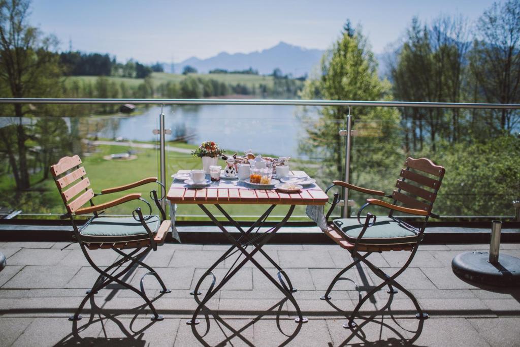 einen Tisch und Stühle auf einem Balkon mit Blick auf das Wasser in der Unterkunft Dreimäderlhaus - Das vegetarische Boutique Hotel in Füssen