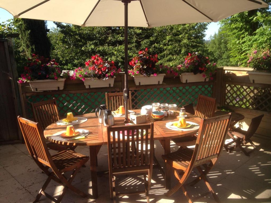 a wooden table with chairs and an umbrella at Le Relais des Malettes Chambres d'hôtes B&B in Francheville