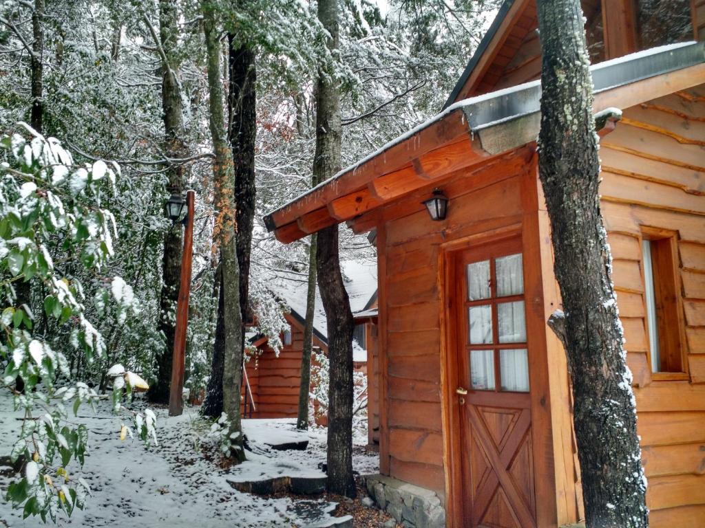 a log cabin with a red door in the snow at Calen-Hue in San Carlos de Bariloche