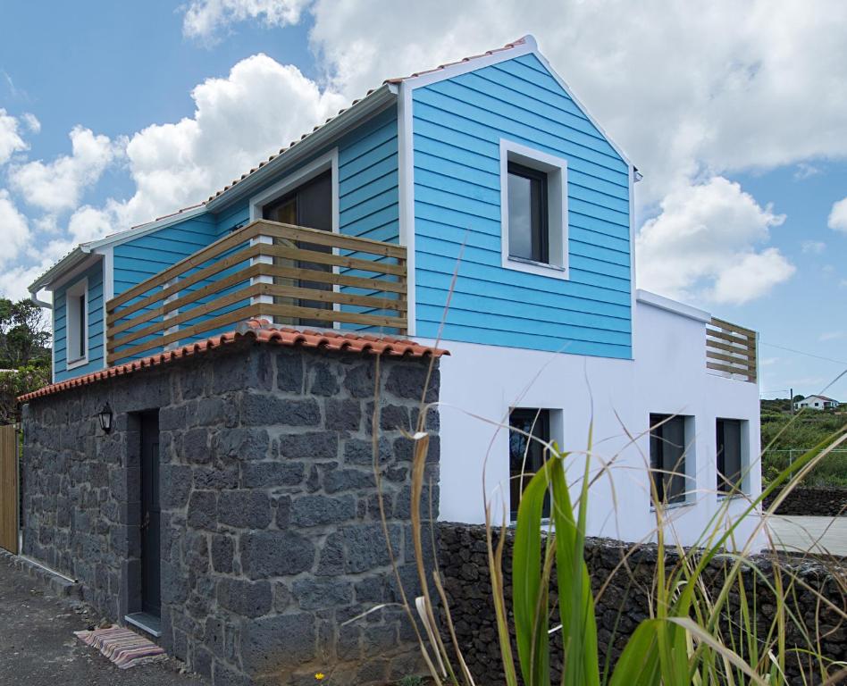 een blauw-wit huis bovenop een stenen muur bij Casa do André (Casas do Capelo) in Fajã
