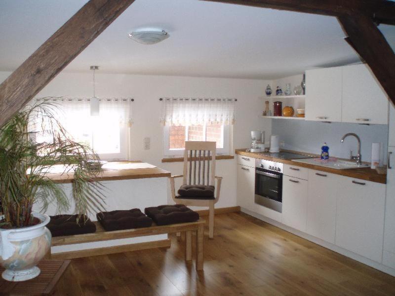 a kitchen with white cabinets and a wooden floor at Stadtferienwohnung in Teterow