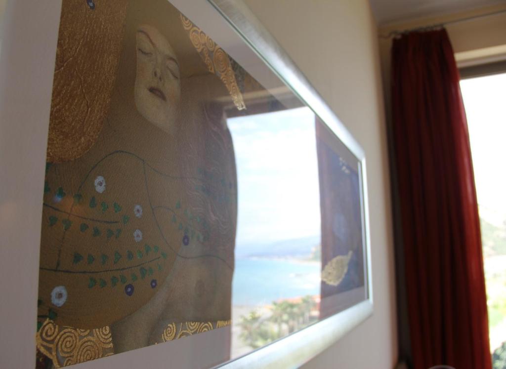een schilderij van een vrouw in een hoed op een raam bij Meridian Hotel in Guardia Piemontese Terme