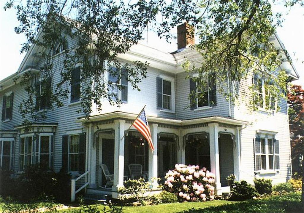 Una grande casa bianca con una bandiera americana sopra. di Isaiah Jones Homestead Bed and Breakfast a Sandwich