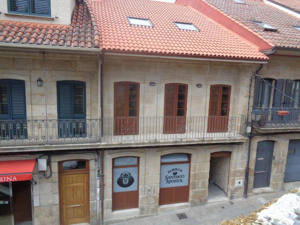 un ancien bâtiment avec un toit rouge et un balcon dans l'établissement Albergue Parroquial Santiago Apostol de Redondela, à Redondela