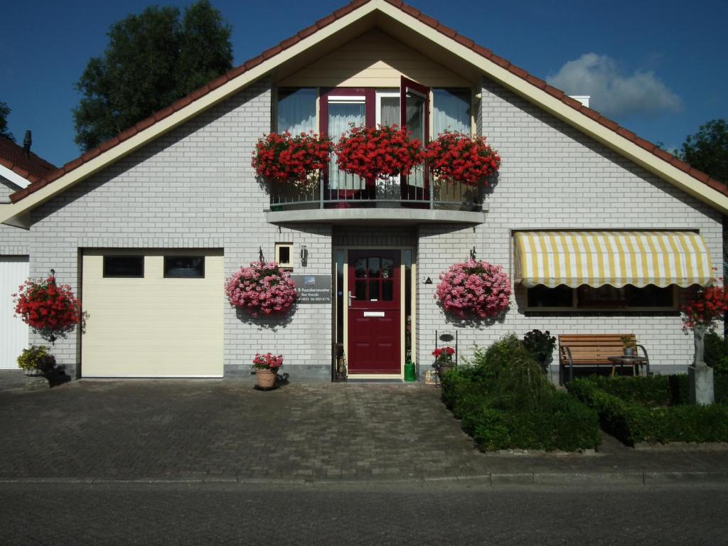 una casa blanca con flores en la puerta en B & B Kaaskenswater, en Zierikzee