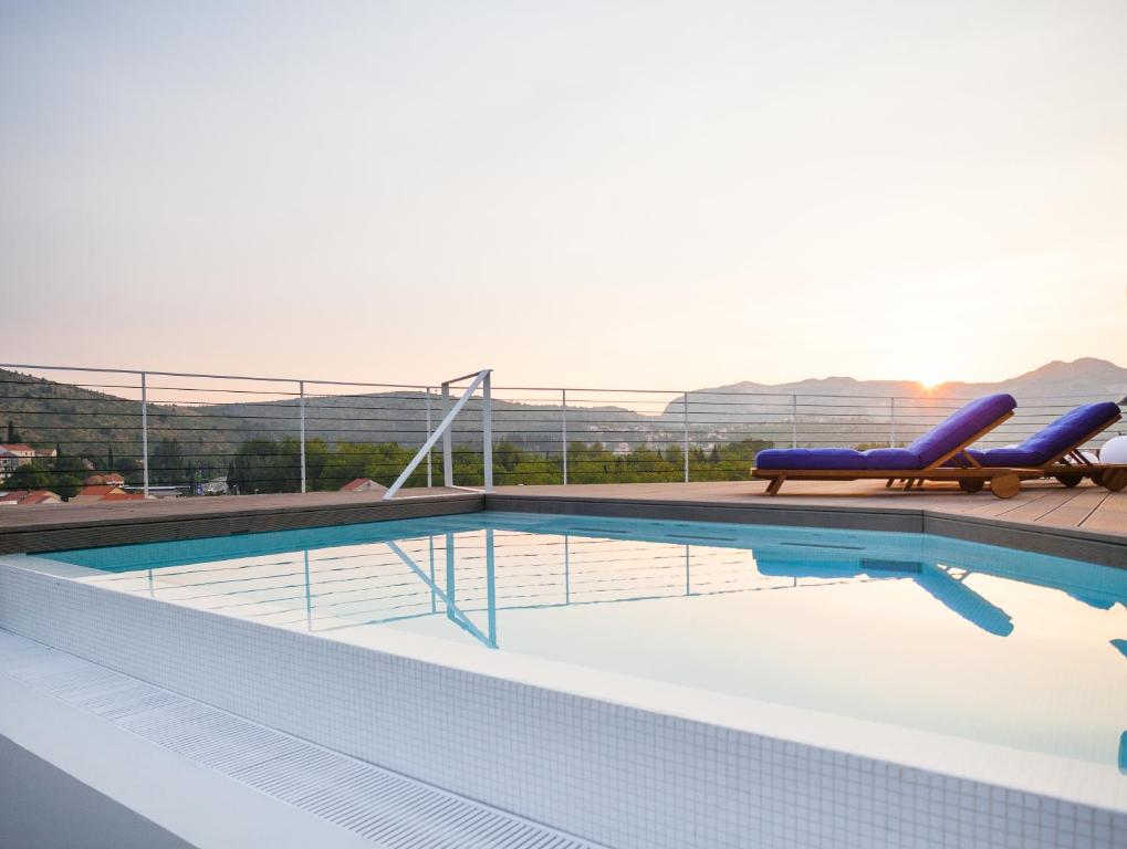 una piscina con 2 tumbonas azules en un edificio en One Suite Hotel, en Mlini