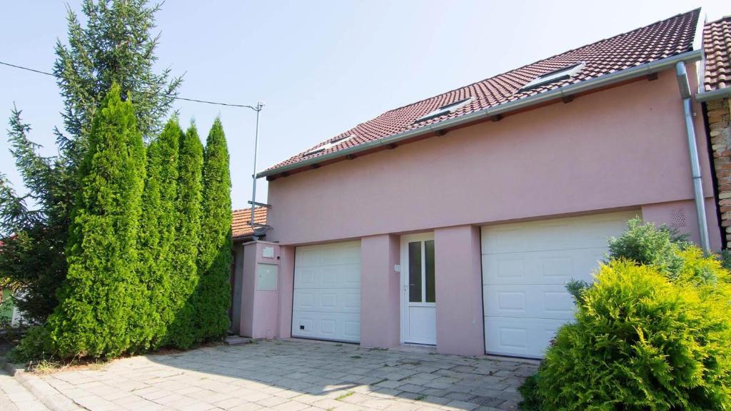 dom z dwoma drzwiami garażowymi i drzewami w obiekcie APARTMÁN CABERNET w mieście Velké Pavlovice