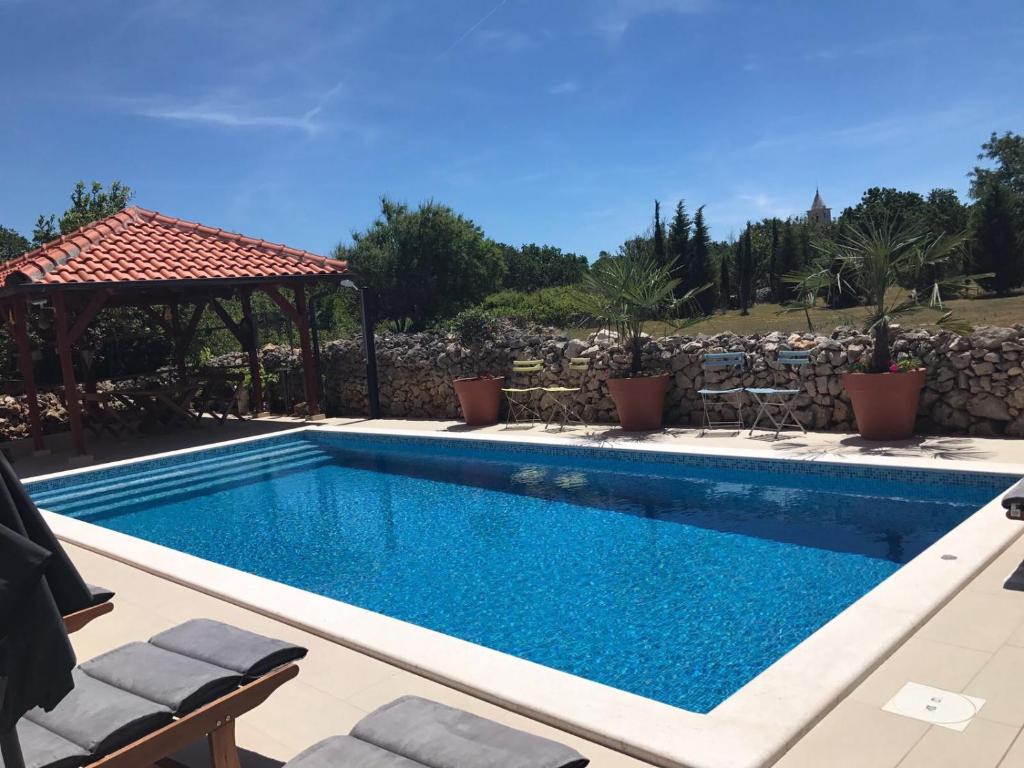 een zwembad met een tuinhuisje en een zwembadvisorvisor bij Apartments Dalmatina in Zaton
