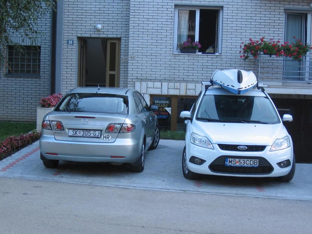 dos autos estacionados uno al lado del otro en un estacionamiento en Guest House Boska en Pančevo