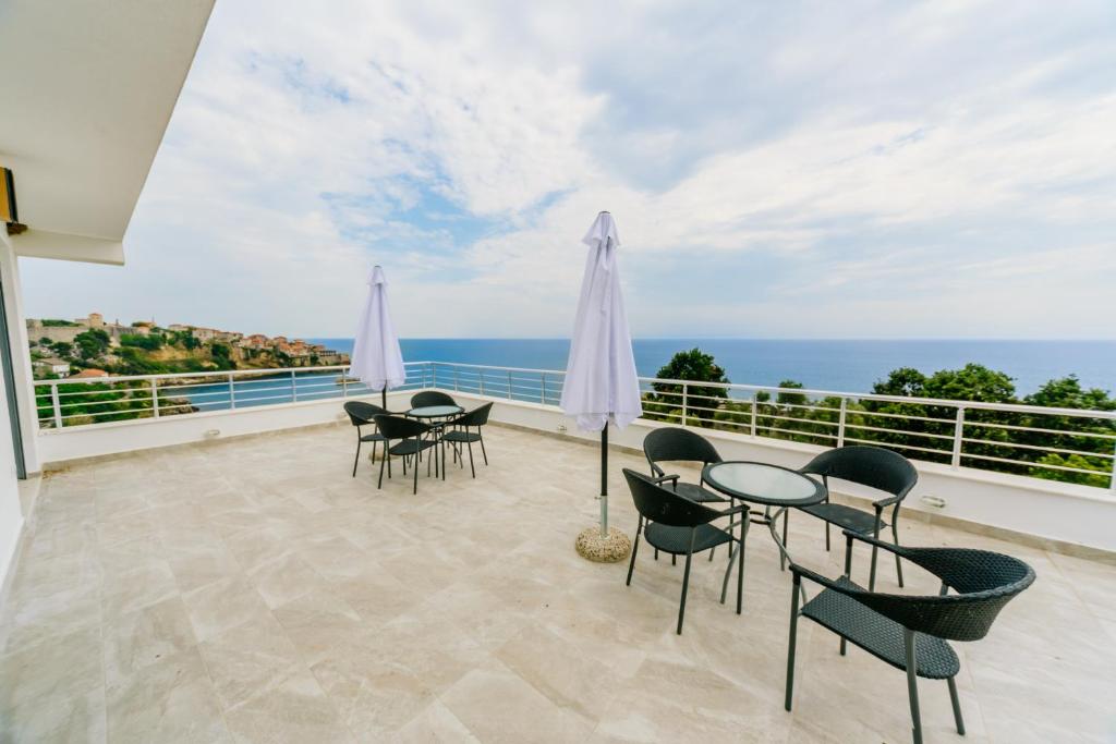een balkon met tafels en stoelen en uitzicht op de oceaan bij Teuta Apartments in Ulcinj
