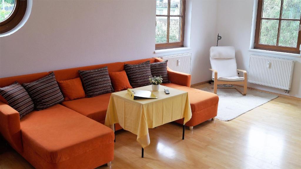 インスブルックにあるFerienwohnung-Apartment Monika in Innsbruck-Iglsのリビングルーム(オレンジ色のソファ、テーブル付)